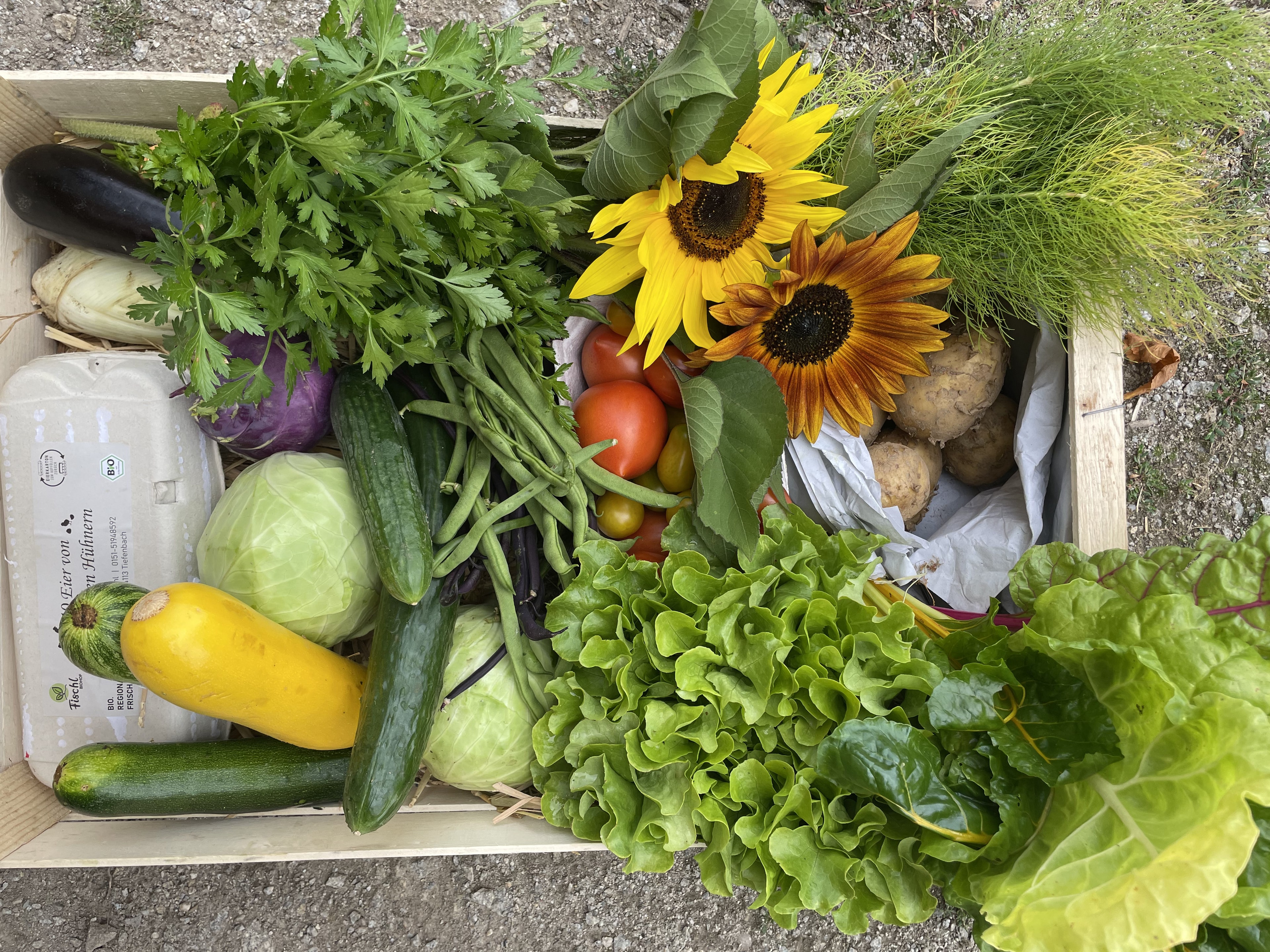 Holzkiste mit frischem Bio-Gemüse, Eiern und Sonnenblumen vom Fischl Biohof in Niederbayern
