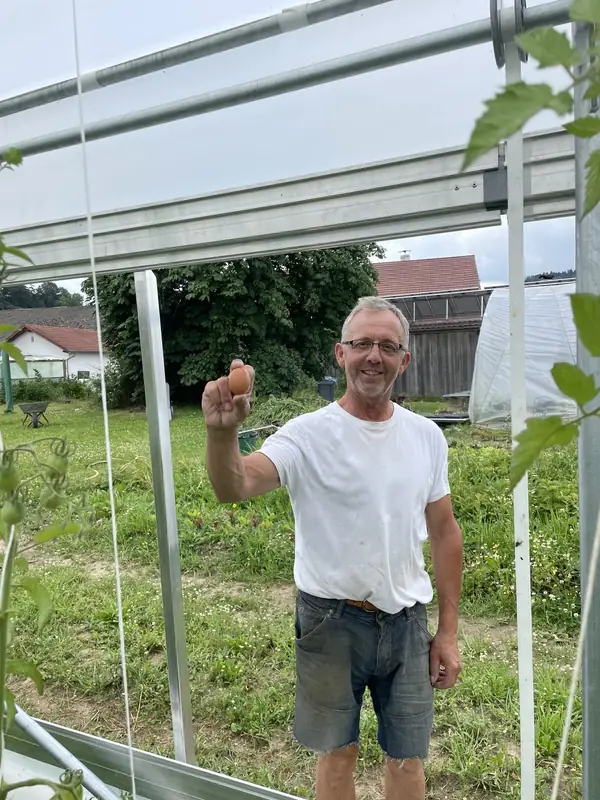 Josef Fischl zeigt ein frisch gelegtes Ei auf dem Fischl Biohof